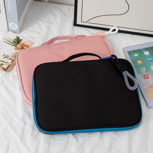 Detail of pink and black portable laptop sleeves on white bedding with a blue zipper accent