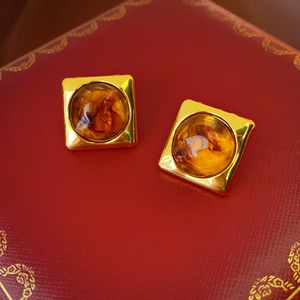 Macro shot of geometric resin earrings with amber finish on gold metal base