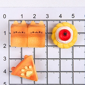 Size reference of miniature cat-shaped toast and cake models on a measuring grid
