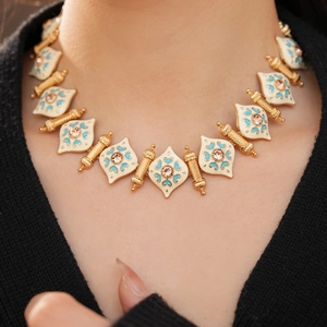 Detailed close-up of vintage enamel necklace with pink gems and gold leaf links