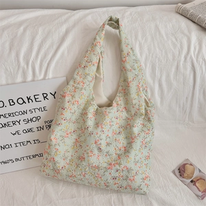 Detail of floral canvas tote bag featuring dense orange flowers on light green fabric