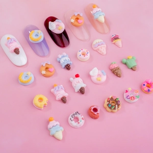 Colorful resin donut and ice cream nail art charms on a pink background for manicure decor