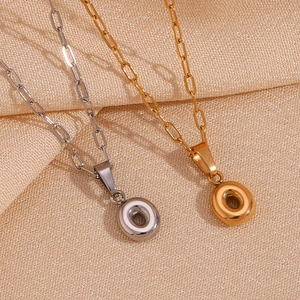Macro shot of gold and silver letter O pendants on minimalist paperclip style chains