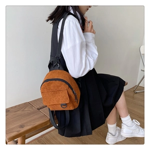 Detailed side view of yellow corduroy mini backpack worn by model in minimalist setting