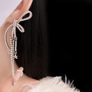Détail de boucles d'oreilles nœud argenté avec strass brillants et étoiles sur mannequin
