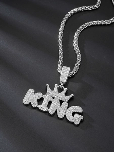 Close-up of silver-toned KING crown pendant with shimmering crystals on twist chain