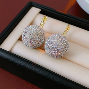Macro detail of gold-tone ball earrings paved with colorful rhinestones on velvet