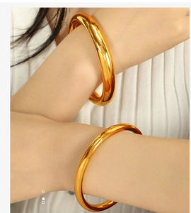 Close-up of minimalist polished gold bangles on wrist with mirror finish texture