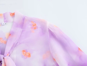 Detailed close-up of purple chiffon blouse neckline with orange floral print and S size label