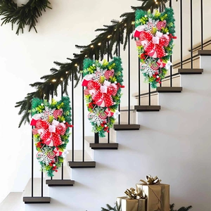 Christmas teardrop swags with red candy canes and bows on a staircase railing