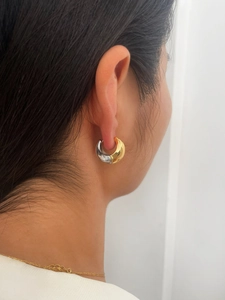 Macro detail of two-tone gold and silver C-shaped drop earrings worn by a model