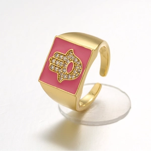 Detail of adjustable gold ring with pink enamel face and crystal Hamsa Hand motif