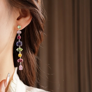 Detail of elegant silver drop earrings with colorful zircon stones worn by a model