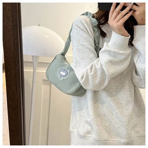 Light green shoulder bag with ruched strap and heart rabbit detail shown on model