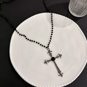 Dettaglio della collana gotica con perline nere, ciondolo a croce decorato e gemma