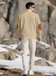 Detail of men's beige knitted sweater with brown elbow patches in outdoor mountain setting