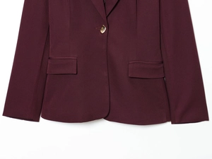 Detail of wine red blazer featuring ornate gold buttons and precise pocket stitching