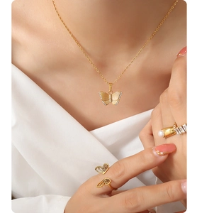 Detail of gold butterfly pendant necklace and matching rings with sparkling zircons