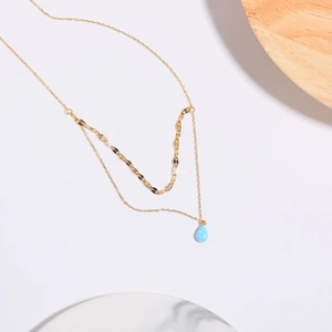 Detail of 18K gold-plated double-layer necklace with light blue opal teardrop pendant