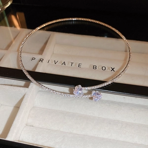 Macro view of a sparkling silver-tone heart crystal choker resting in a jewelry box.