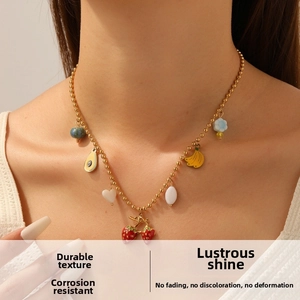 Detail of gold beaded necklace featuring cute enamel strawberry and avocado fruit charms