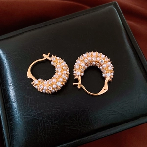 Close-up of 18k gold plated hoop earrings with pearls and crystals on black leather