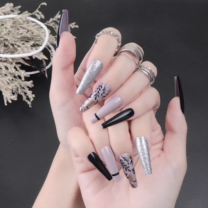 Long coffin fake nails with glitter and black leaf patterns on purple and black finish
