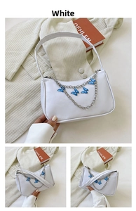 Detail of white PU underarm bag featuring silver chain and blue butterfly charms