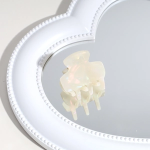 Detailed view of mini iridescent white acetate hair claw clip on heart mirror
