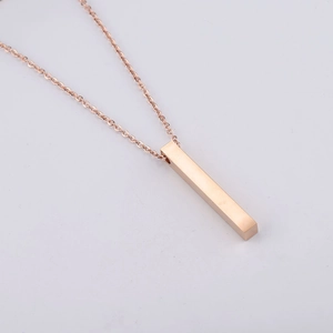 Dettaglio ravvicinato di un ciondolo a barra solida in oro rosa su collana minimalista