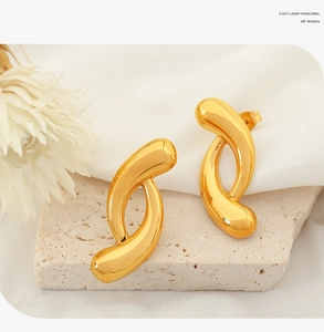 Detail of gold geometric irregular hoop earrings on an elegant white textured background