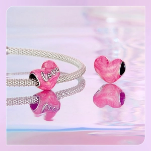 Macro shot of pink marble texture heart charms with love engraving on silver mesh bracelet