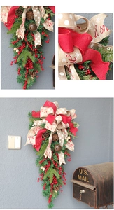 Close-up of rustic Christmas teardrop swag with red berries, pine cones and bow