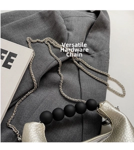 Detail of silver pebble grain mini bag with matte black beads and metal chain