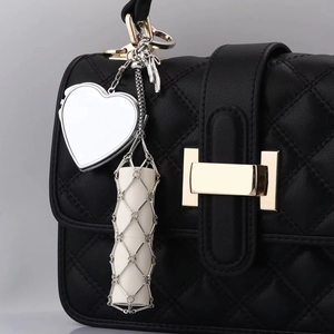 Detailed close-up of a silver mesh lipstick holder pendant on a black quilted handbag