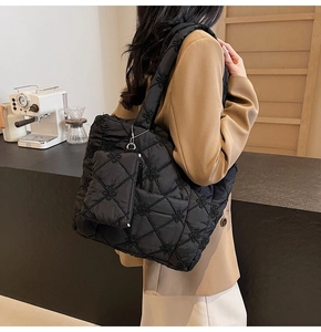 Detail of black quilted tote bag with floral embroidery and detachable mini pouch