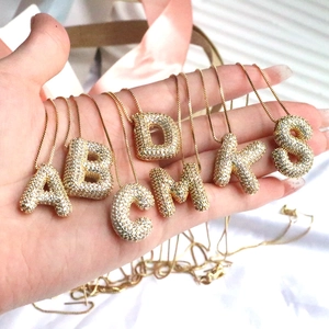 Macro shot of 18K gold plated bubble initial pendants with micro-pave cubic zirconia