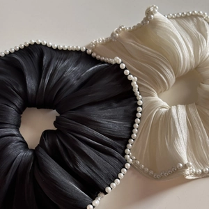 Close-up of black and cream satin scrunchies with elegant pearl edge detailing