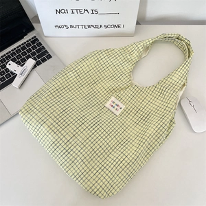 Top view of blue plaid cotton tote bag with sozakka beaute label on white workspace