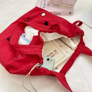 Detail van rode canvas tas met trekkoord, konijnenborduurwerk en grote opbergruimte