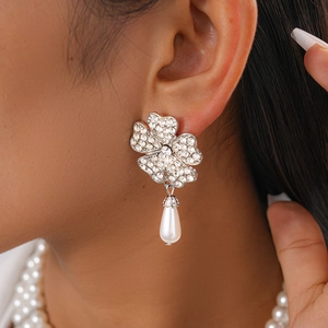 Close-up of silver flower earrings with rhinestones and pearl pendant on a model