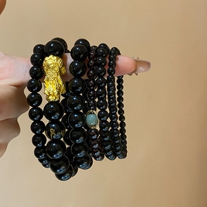 Macro shot of obsidian beads with golden Pixiu charm and engraved Sanskrit mantras