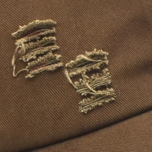 Close-up of distressed denim baseball cap showing retro ripped holes and twill texture