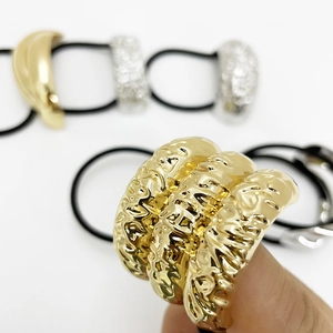 Close-up of golden elastic hair tie featuring irregular textured metal bow ornament