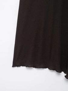 Nahaufnahme des schwarzen Strickrocks mit weichem Rüschensaum und feiner Texturdetails