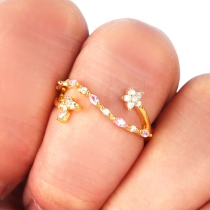 Elegant gold open ring with floral design and pink stones worn on a female hand