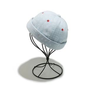 Close-up of light blue paisley docker hat with red embroidered eyelets on a stand