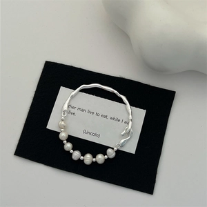 Detail of baroque pearl and irregular silver branch bracelet on a black decorative card