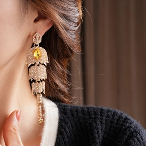 Close-up of vintage gold tassel earrings with pearls and a yellow teardrop gemstone
