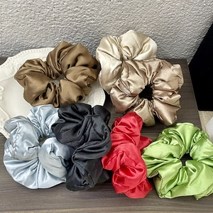 Detailed collection of silk satin scrunchies in diverse elegant colors on a wooden surface